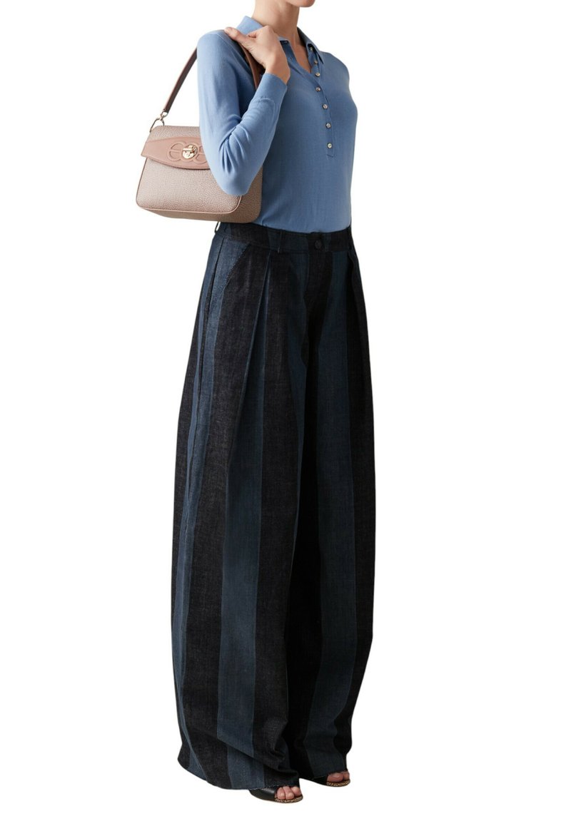 Haut à manches longues bleu clair avec boutons, associé à un pantalon taille haute, plissé, à jambes larges en denim foncé. Petit sac à main avec détails texturés.