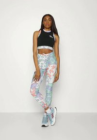 Top preto cropped com alças coloridas, leggings estampadas em tons pastéis, com desenhos abstratos, combinadas com sapatilhas de desporto azul claro.