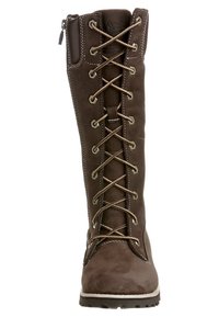 Hnědá kotníková bota se zavazováním, vysokým svrškem, vyrobená z materiálu připomínajícího semiš, s kontrastními tkaničkami a prošitím, a gumovou podrážkou.