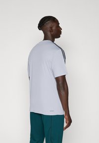 Grijze atletische t-shirt met een ronde hals, korte mouwen en zwarte zijstrepen. Gemaakt van lichtgewicht, ademend materiaal.