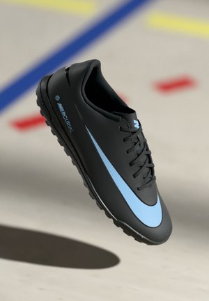 Black soccer shoe with a smooth design, featuring a light blue swoosh, black laces, and a textured sole with prominent traction studs.