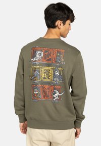Sudadera verde oliva con cuello redondo; presenta un colorido diseño gráfico de perros en vagones de tren en la parte posterior. Material de algodón, ajuste relajado.