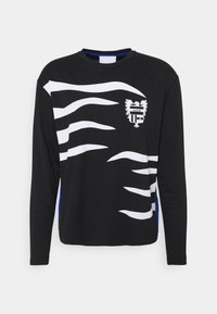 Schwarzes Langarmshirt mit weißen Wellenmustern, blauen Seitenakzenten und einem Schildlogo mit einem zweiköpfigen Adler.