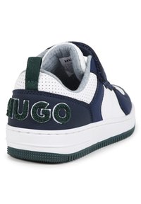 Marineblå og hvite sneakers med en teksturert overflate, med en grønn strikket "HUGO" logo på hælen og en hvit gummisåle med grep mønster.