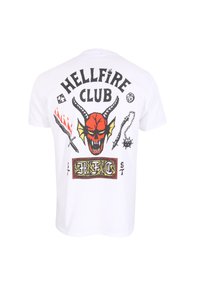 Bílá bavlněná tričko s barevným potiskem červené lebky ďábla, plameny a různými symboly s textem "HELLFIRE CLUB" na zádech.
