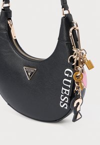 Czarna torebka na ramię ze sztucznej skóry z złotymi okuciami, zamkiem błyskawicznym i ozdobnym breloczkiem w formie klucza z różnymi kształtami i kolorami.