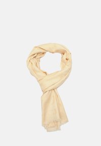 Écharpe beige en tissu doux, avec un motif subtil et des extrémités frangées. L'écharpe est enroulée en forme de boucle.