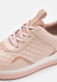 Jasnoróżowy trampki z teksturowanym wzorem MK, sznurowanym fasonem, wyściółką z poduszką i grubą białą i różową podeszwą z pętelką do łatwego zakładania.