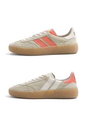 Paire de baskets en daim beige avec semelles en gomme ; l'une a des bandes orange et un talon orange, l'autre des bandes blanches et une languette de talon orange.