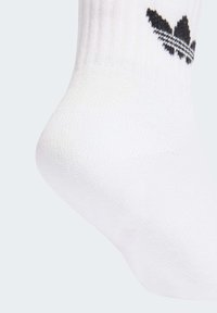 Λευκή βαμβακερή αθλητική κάλτσα με ριμπ ύφανση, που φέρει το μαύρο λογότυπο adidas και δύο μαύρες ρίγες κοντά στην κορυφή.