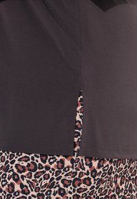 Tmavý top s krátkými rukávy, s bočním rozparkem odhalujícím spodek s leopardím vzorem v béžových a hnědočervených tónech. Hladká textura látky.