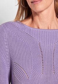 Lila Strickpullover mit gerippter Textur, offenen Maschen und weitem Ausschnitt. Das Material scheint leicht und atmungsaktiv zu sein.