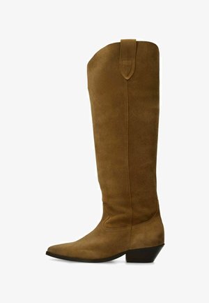Bottes en daim marron montant jusqu'au genou, avec un bout pointu, un petit talon et un détail en boucle en haut. Texture lisse et design épuré.