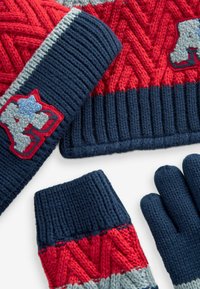 Knit hat, gloves, and wrist warmers in red, navy, and gray. Hat features a zigzag pattern; gloves and wrist warmers have ribbed cuffs and accent detailing.