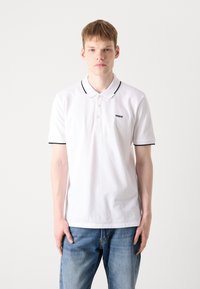 Polo bianco con accenti neri sul colletto e sulle maniche, caratterizzato da un'apertura a tre bottoni e da un piccolo logo nero sul petto.