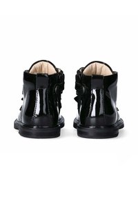 Stivali alla caviglia in pelle patent nera con una texture liscia e lucida. Presentano una chiusura a bottoni e dettagli decorativi a fascia sul retro.