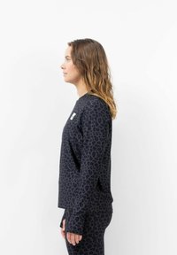 Langärmliges schwarzes Oberteil mit einem Leopardenmuster. Hergestellt aus weichem Stoff, mit Rundhalsausschnitt und gerippten Bündchen.