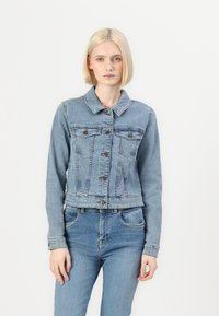Chaqueta de mezclilla azul claro con un collar clásico, bolsillos frontales y cierres de botones. Presenta un diseño recortado y una textura suave.