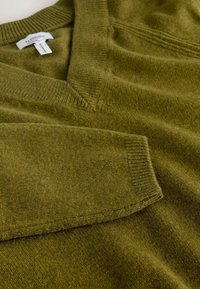 Olive green knit sweater with a V-neck, ribbed cuffs, and textured fabric. Smooth surface with a relaxed fit and subtle stitching detail.