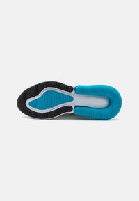 Semelle d'une basket avec des grips en caoutchouc noirs et bleus sur une base blanche, conçue pour l'adhérence et le confort.