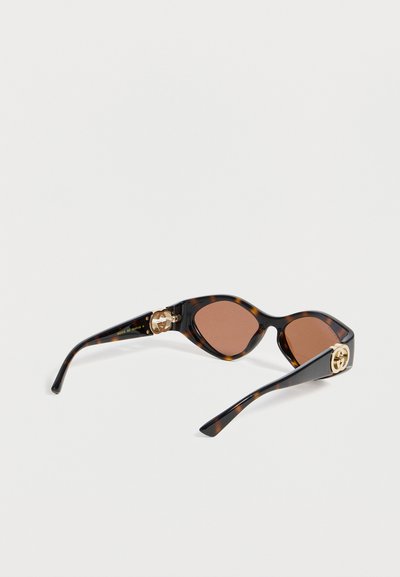 Γυαλιά ηλίου σε σχήμα γατίσιου ματιού με καφέ φακούς και χρυσά διπλά λογότυπα G στα μαύρα βραχίονες.