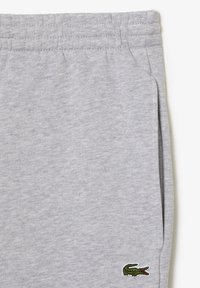 Pantaloni de trening gri din bumbac, cu talie elastică cu nervuri, buzunare laterale și un mic logo brodat de crocodil verde pe coapsă.