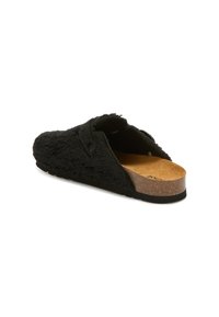 Černé texturované pantofle na slip-on s odpruženou korkovou stélkou, s zakřiveným tvarem a minimalistickým designem, ideální pro nošení uvnitř.