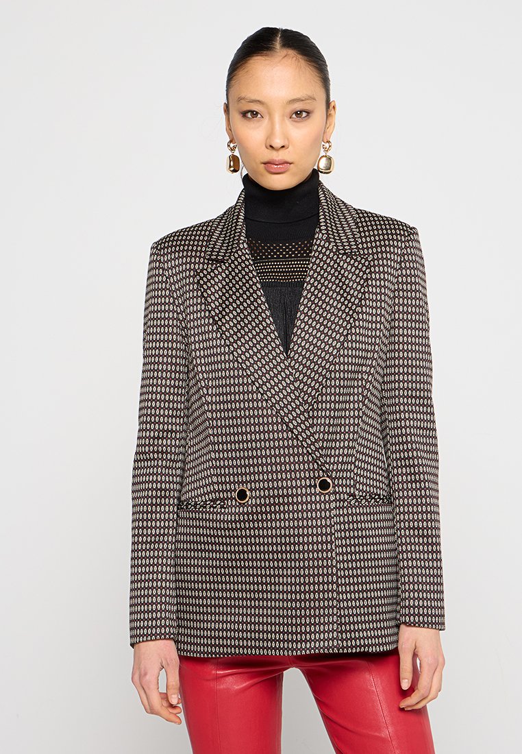 Schwarzer Doppelreiher-Blazer mit einem geometrischen Muster in Weiß und Rot. Besitzt spitze Revers und Akzente in Goldfarbe.
