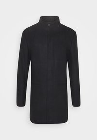 Černý kabát z texturované látky s vysokým límcem, přímým střihem a dvěma předními kapsami. Má střední zapínání na knoflíky.