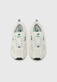 Zapatillas de running blancas con parte superior de malla, detalles en color verde azulado y logo. Presentan cordones, un cuello acolchado y suela de goma negra.