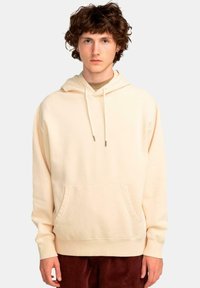 Sudadera color crema hecha de una tela suave, con un bolsillo delantero, capucha con cordón y un ajuste relajado. Textura suave, diseño minimalista.