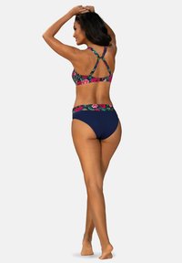 Góra bikini w kwiatowy wzór z paskami zaplatanymi na krzyż z tyłu; granatowe majtki z wysokim stanem. Kluczowe kolory: żywe odcienie różu, zieleni i granatu. Gładka faktura.