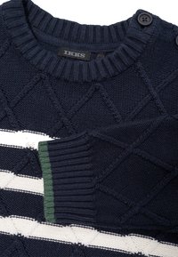 Maglione lavorato a maglia blu navy con motivo a rombi texturizzato, strisce orizzontali bianche, accento verde sul polsino e scollatura a coste arrotondata.