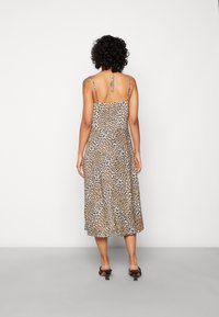Robe midi à imprimé léopard avec fines bretelles, présentant une coupe ample et un tissu lisse. Le dos est échancré et offre une silhouette décontractée.