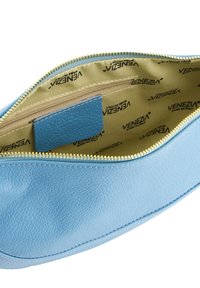Hellblaues Lederetui mit strukturiertem Finish, goldener Reißverschluss und beiger Innenauskleidung, die ein wiederholtes Markenlogo-Muster aufweist.