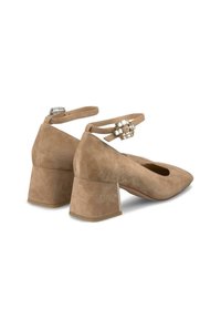 Zapatos de tacón de gamuza beige con punta afilada y tacón grueso. Presentan una correa para el tobillo con un acento decorativo de gema transparente.