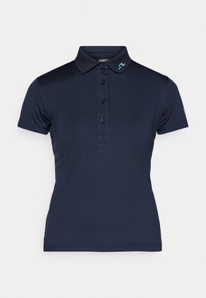 Navy polo skjorte laget av glatt stoff, med klassisk krage, tre knapper og en logo brodert i lyseblått på kragen.