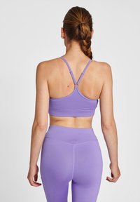 Lila sportcrop-top med tunna axelband och en horisontell sömn, tillsammans med matchande högmidjade leggings i ett mjukt, elastiskt material.