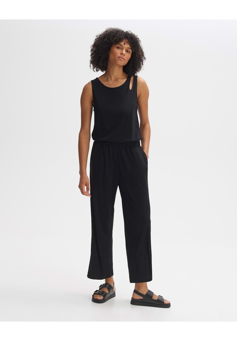 Schwarzer ärmelloser Jumpsuit mit rundem Ausschnitt, der auf einer Schulter ein Ausschnittdetail aufweist und einen elastischen Bund für zusätzlichen Komfort bietet.