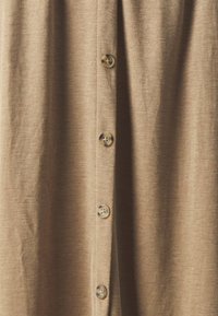 Camicia con bottoni in tessuto marrone chiaro, con cinque bottoni sul davanti, dalla consistenza liscia e un sottile motivo melangiato.