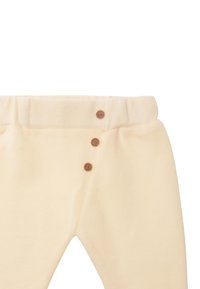 Cremfarbene Baumwollhose mit strukturiertem Finish, breitem Bund und drei dekorativen braunen Knöpfen auf der Vorderseite.