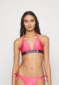 Ružový rebrovaný bikiny set obsahujúci trojuholníkový halter top s čiernym pásikom Calvin Klein a zodpovedajúce spodné časti s viazaním na bokoch.