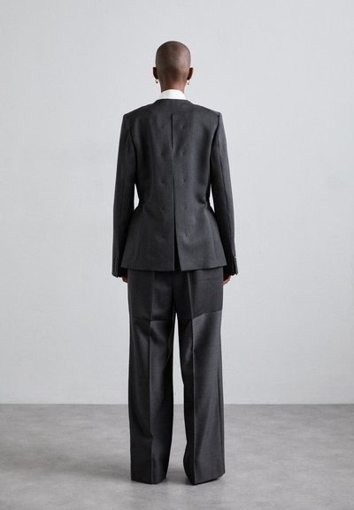 Szürke, szabott öltöny strukturált, dupla gombos blézerrel és széles szárú nadrággal. Gyapjúkeverék anyag, látható varrásokkal és hátsó szellőző részlettel.