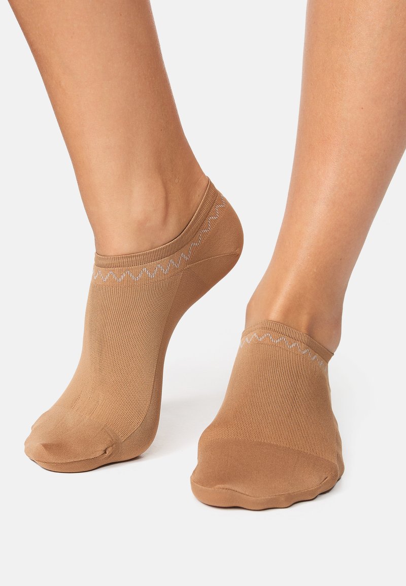Calzini alla caviglia beige realizzati in tessuto traspirante, caratterizzati da un motivo strutturato e un morbido polsino superiore con un delicato accento smerlato.
