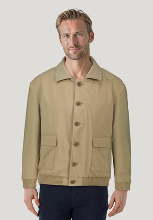 Beige Hemdjacke mit großen Fronttaschen, gerippten Bündchen, flachem Kragen und Holzknöpfen, aus einem glatten Stoff gefertigt.