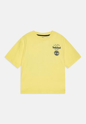 Geel Timberland T-shirt met korte mouwen, ronde hals en zwart logo en tekst op de linkerborst met de tekst "N.H USA Timberland EST 1973."