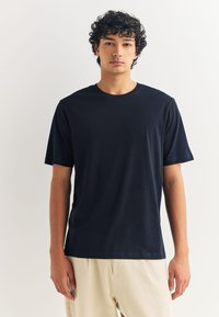 Tumesinise värvusega puuvillane lühikeste varrukatega T-särk, ümar kaelus ja sile tekstuur. Omadusteks on lõdvestunud istuvus ja lihtne disain.