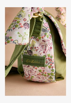 Sac en tissu vert avec un panneau en tissu à motif floral. Il présente un anneau doré et une étiquette verte avec "Cath Kidston" en lettres dorées.