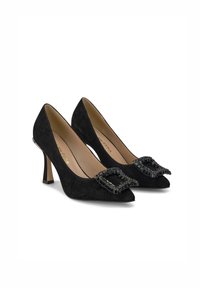 Tacchi alti in suede nero con punta affilata, caratterizzati da una fibbia nera decorata a forma quadrata sul davanti e un tacco slanciato di media altezza.
