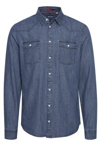 Blå denimskjorte med lange ermer, knapper i kragen, to brystlommer og kontrasterende sømmer langs skuldrene og knappeåpningen.